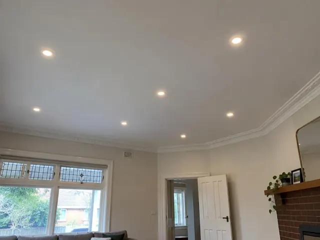 Ceiling with recessed LED downlights in a lounge room with cornice and fireplace in Hamilton
